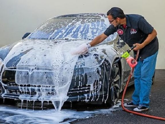 Thực hiện phun dung dịch rửa xe lên bề mặt xe ô tô